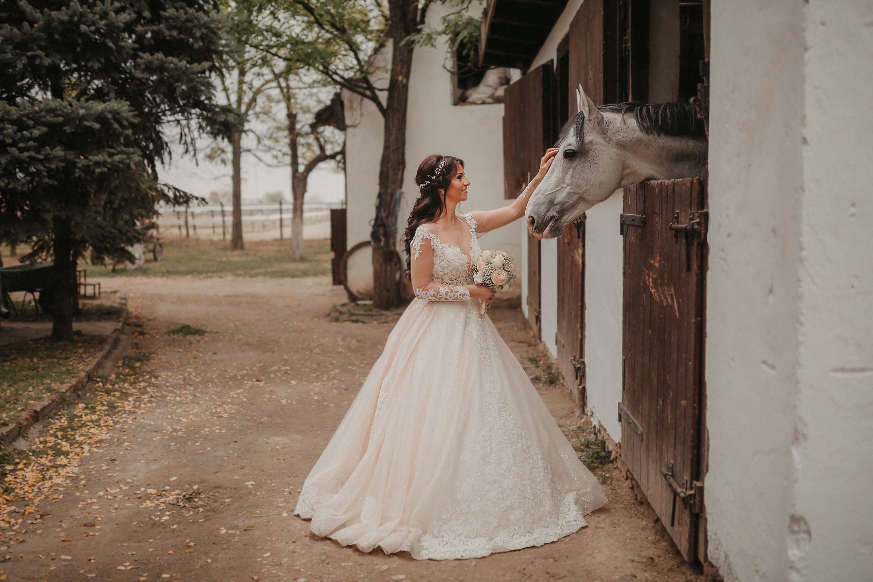 Nach der Bearbeitung mit dem Rustic-Wedding-Preset: warmes, erdiges Hochzeitsfoto einer Braut vor einem Stall